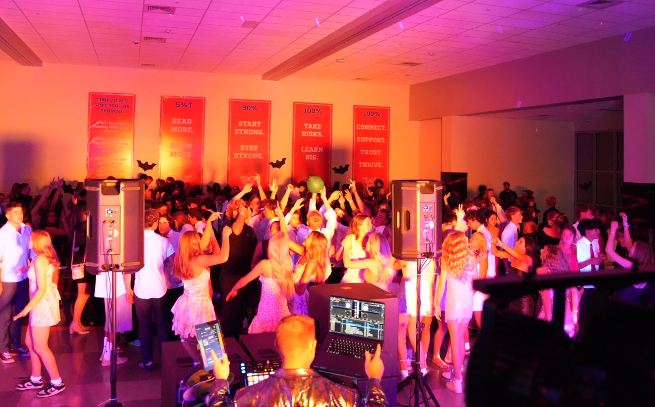 High school dance with packed floor under colorful lights